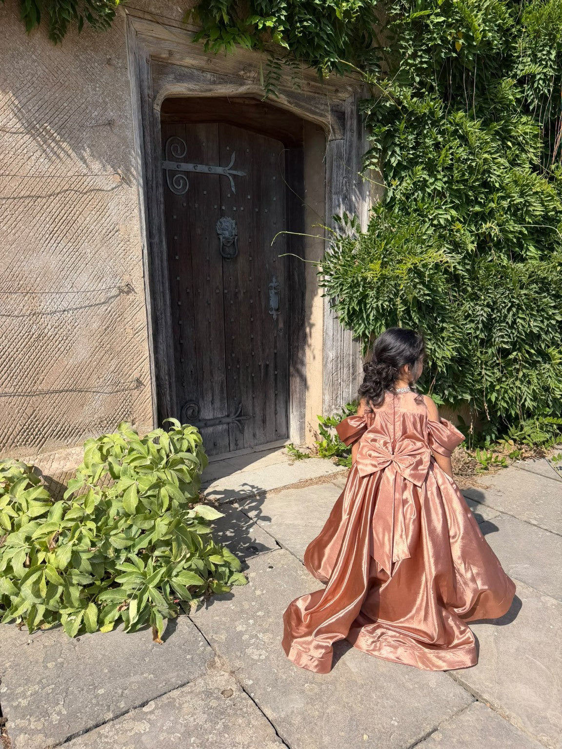 Rosalie gown photographed from behind at an ivy-covered stone doorway