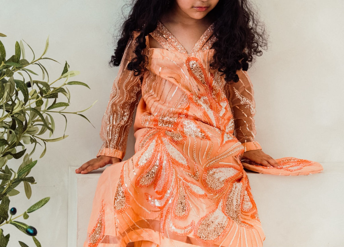 Zaria occasion dress shown seated, highlighting its sweeping embroidered detailing